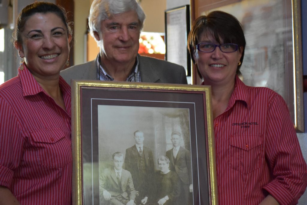 Criterion Hotel staff members Jacqui Swift-Ross and Kylie Jenner with owner Tony Prentice and a photograph of the hotel's original owner Mrs Allman, who reportedly haunts the hotel.